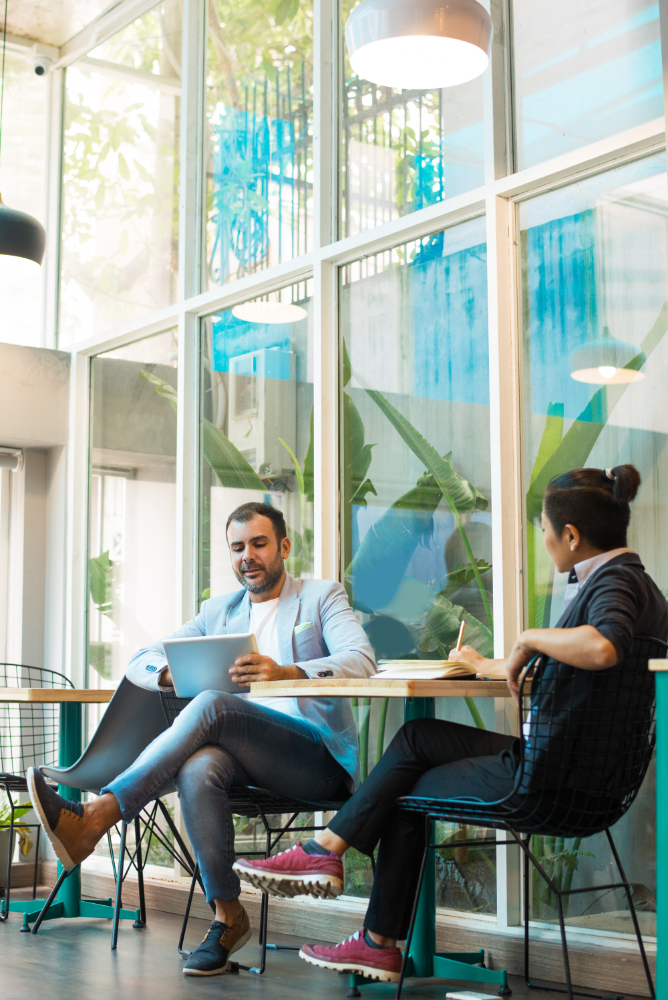 Two colleagues reviewing work at a sunlit café table