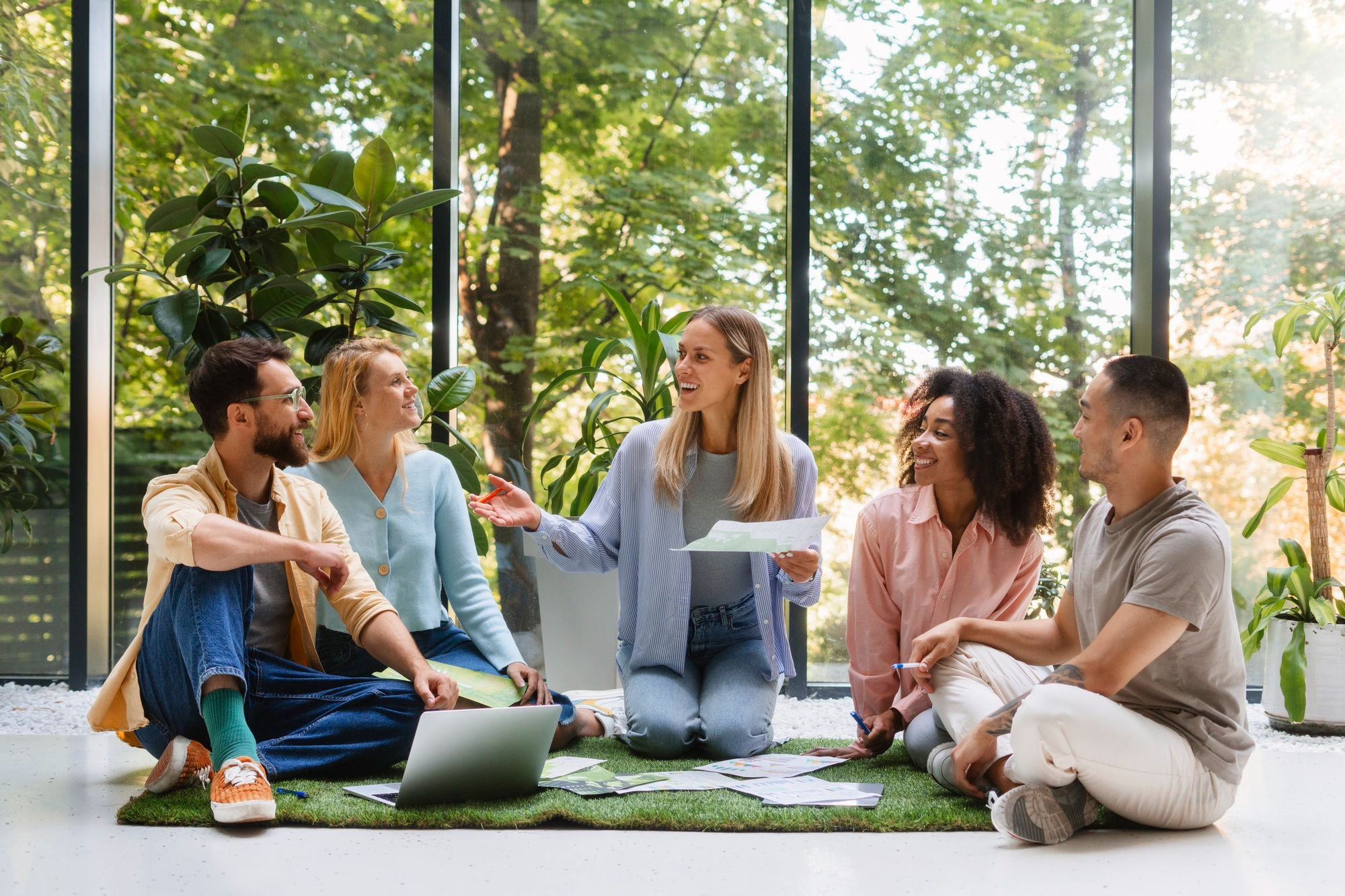 A team collaborating on the floor of a bright, plant-filled studio